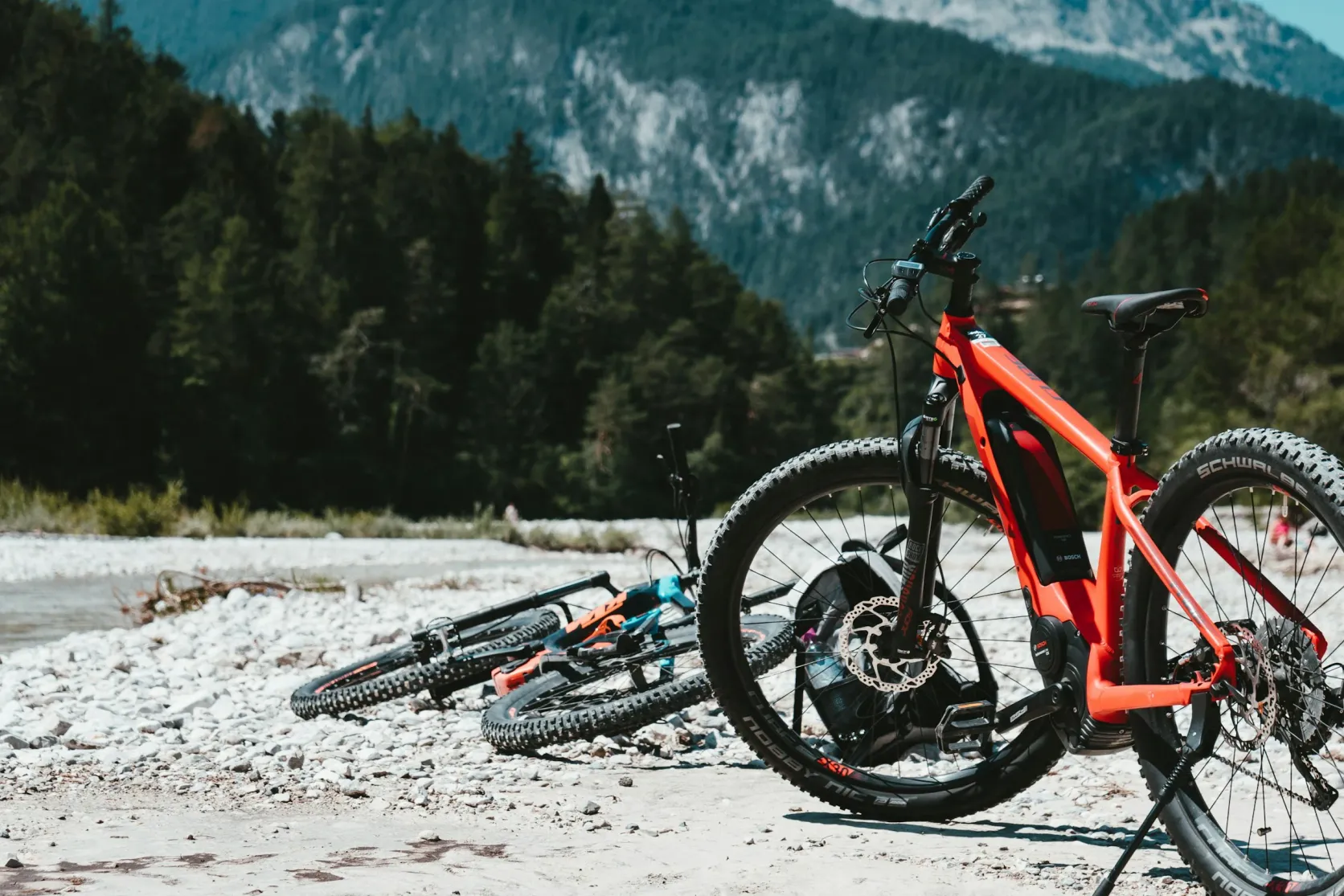 Electric mountain bike with a down-tube lithium battery pack on a rocky riverbed in the mountains
